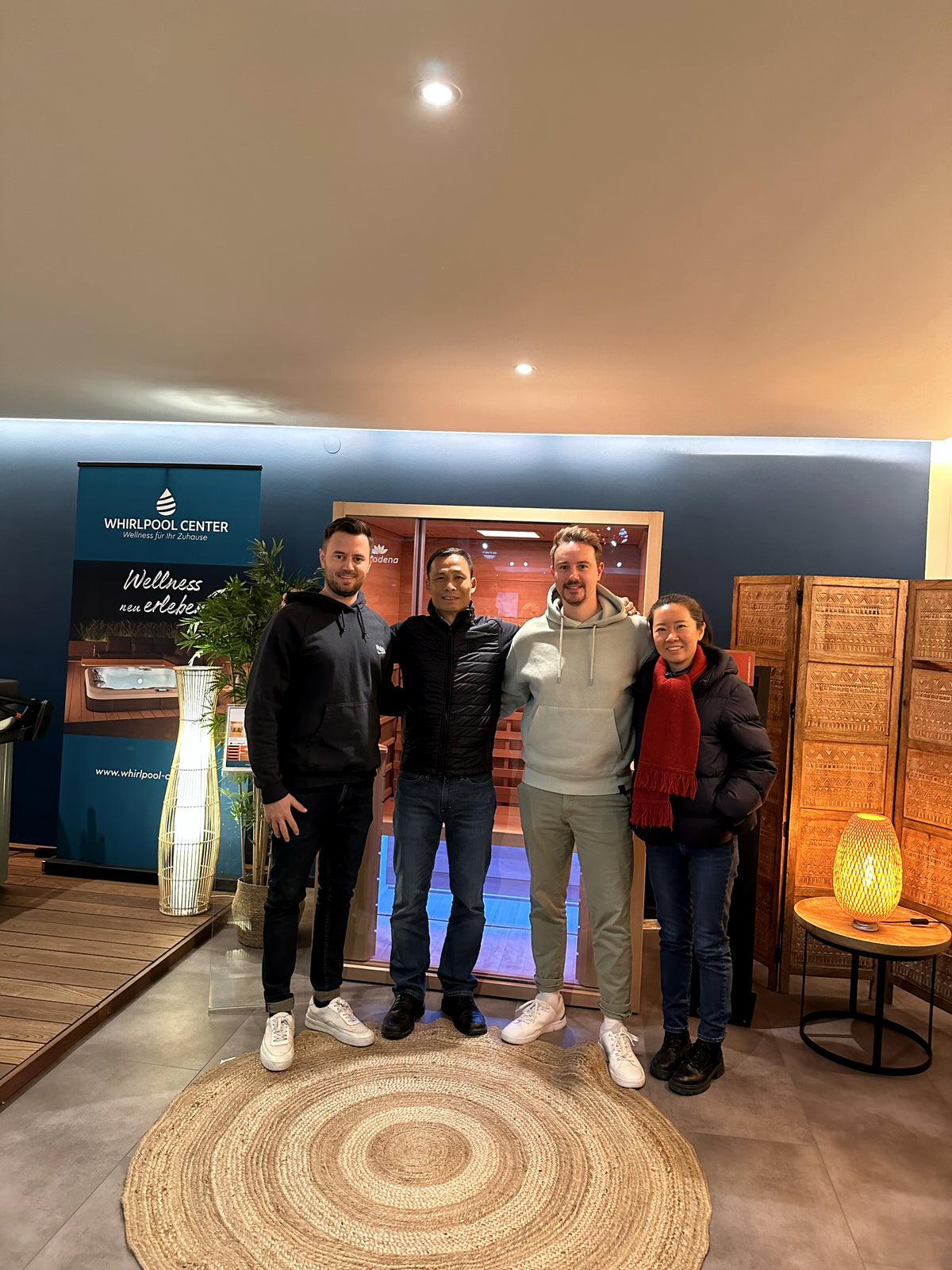 Vier Personen bei einem Partnerbesuch im Whirlpool-Center-Showroom vor einer Saunakabine