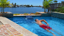 Mann schwimmt in einem Gartenpool mit Gegenstromanlage und Blick aufs Wasser