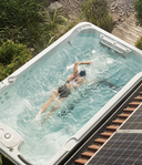 Schwimmerin im Swim Spa neben Solarmodulen aus der Vogelperspektive