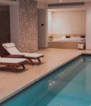 Innenpool mit Liegen und Whirlpool in einem modernen Wellnessraum