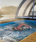 Person beim Kraulen in einem überdachten Pool am See