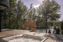 Sprudelnder Whirlpool auf einer Holzterrasse mit herbstlichen Bäumen und Seeblick