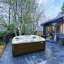 Jacuzzi J-475 Whirlpool mit dunkler Verkleidung auf einer Gartenterrasse