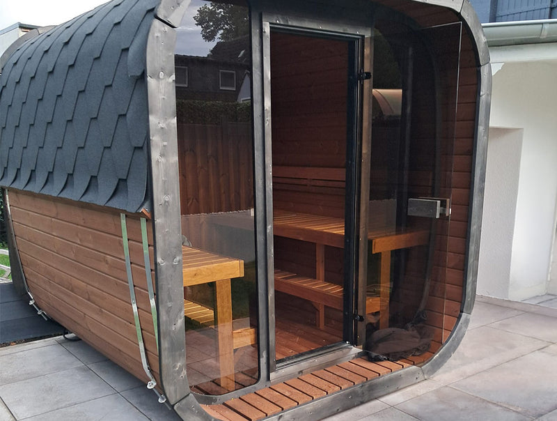 Kaunis Gartensauna mit Glasfront und sichtbaren Holzbänken auf einer Terrasse