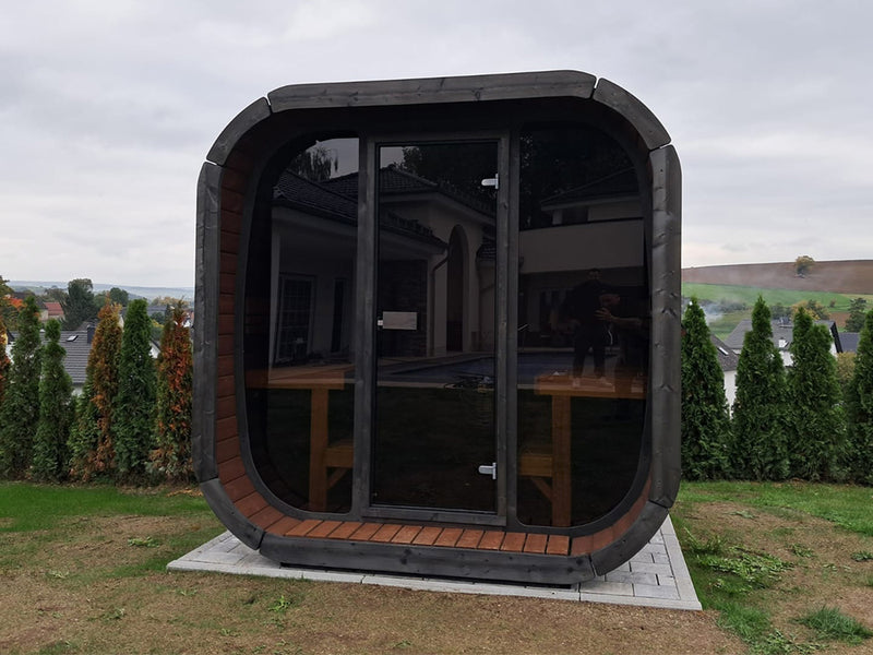 Dunkle Kaunis Gartensauna mit Glasfront auf einer Anhöhe im Garten