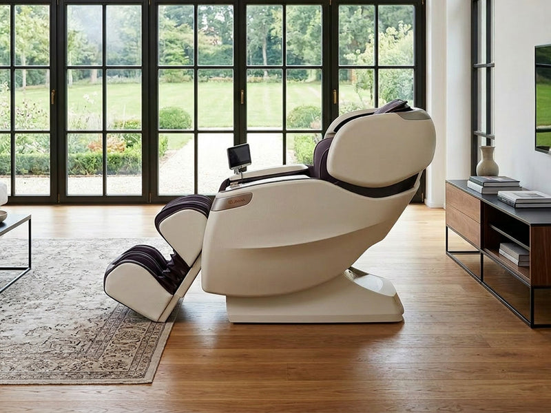 Seitenansicht eines hellen Massagesessels mit Beinauflage und Bedienbildschirm in einem Wohnzimmer