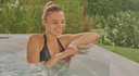 Lächelnde Frau bedient die Steuerung eines Outdoor-Whirlpools