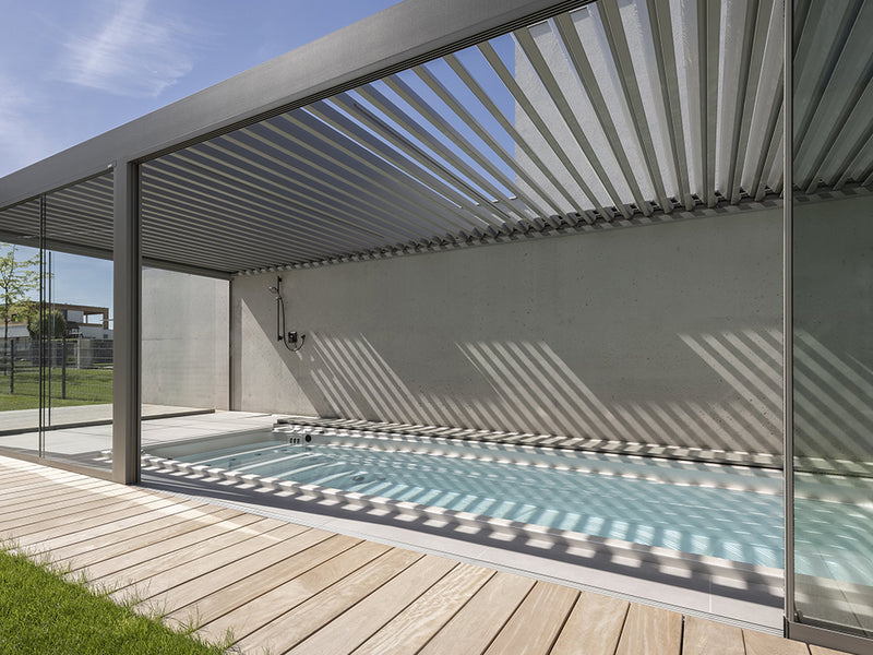 Langer Swim-Spa unter einer Lamellenpergola auf einer modernen Holzterrasse