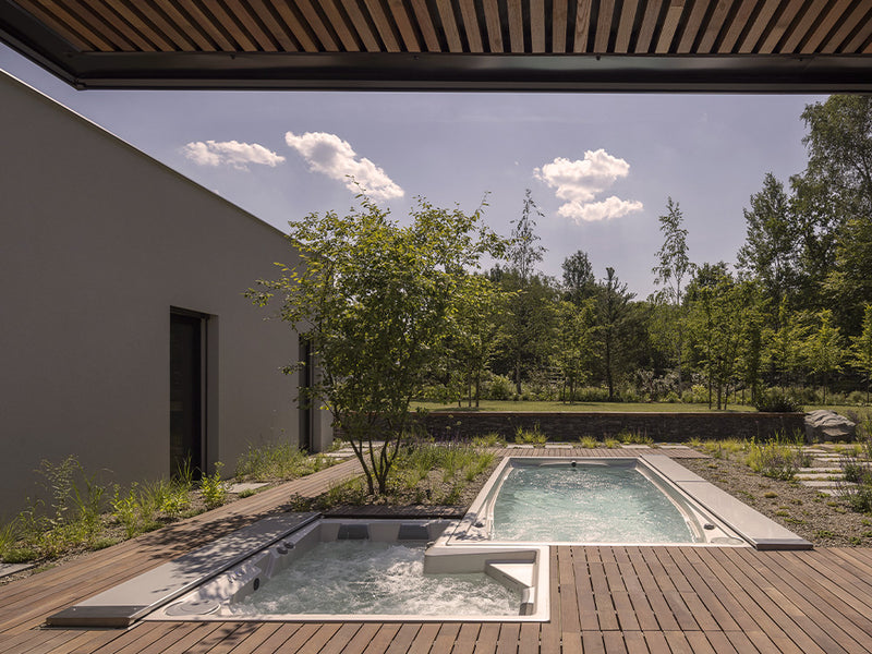 Zweizonen-Swim-Spa mit sprudelndem Whirlpool- und Schwimmbereich auf einer Holzterrasse