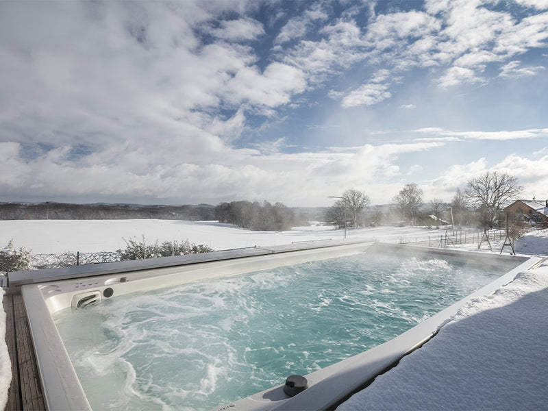 Dampfender Swim-Spa im Schnee mit Blick über eine winterliche Landschaft