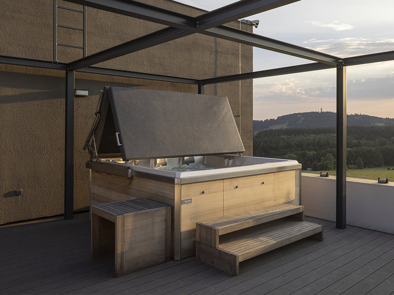 Outdoor-Whirlpool mit geöffneter Abdeckung auf überdachter Terrasse mit Weitblick