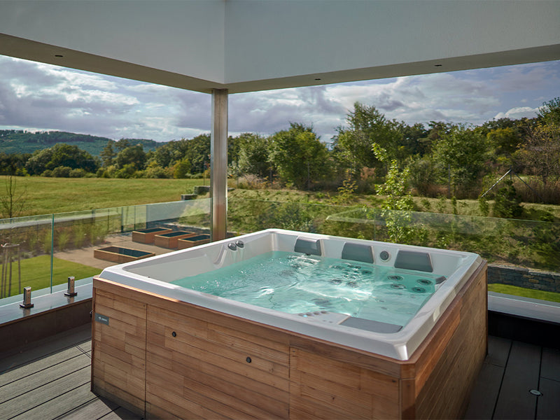 Whirlpool mit Holzverkleidung auf einer überdachten Terrasse mit weitem Landschaftsblick