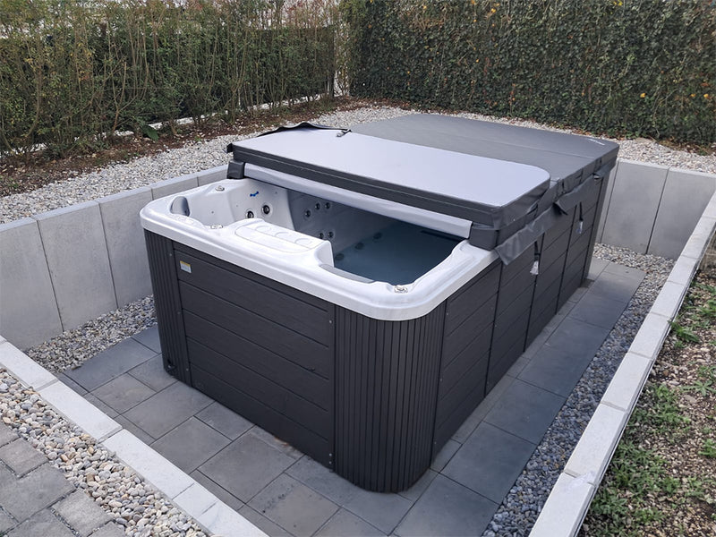 Teilweise geöffneter VIVO SPA Waterfit Swim-Spa in einer mit Kies eingefassten Terrassenmulde