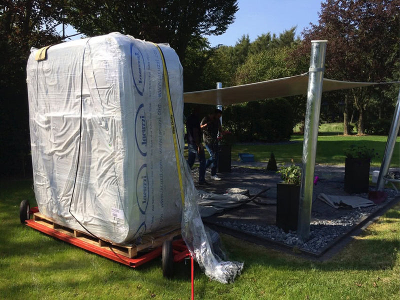 Aufrecht verpackter Whirlpool auf einem Transportwagen im Garten