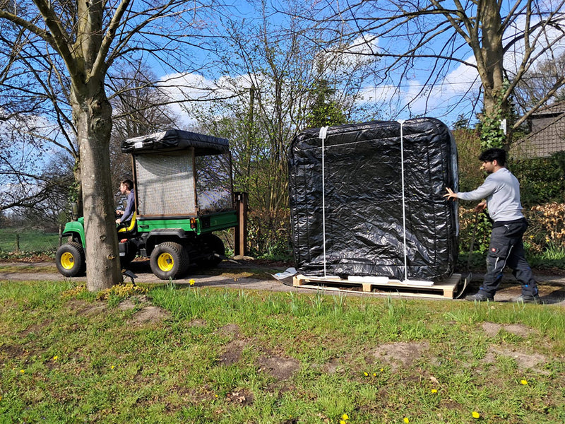 Mitarbeiter schiebt einen aufrecht verpackten WELUXIA Whirlpool auf einer Palette zu einem Transportfahrzeug