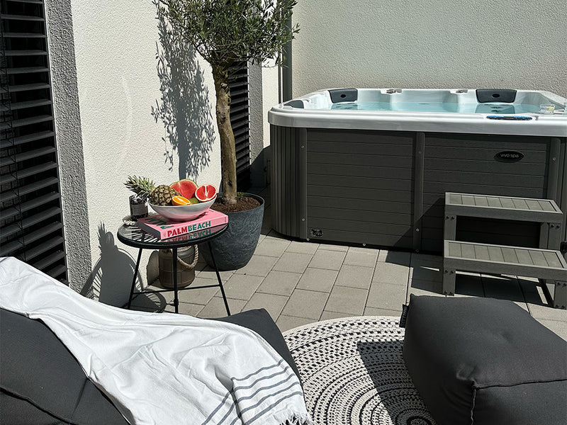 WELUXIA Whirlpool mit Einstiegstreppe und Liegebereich auf einer sonnigen Hausterrasse