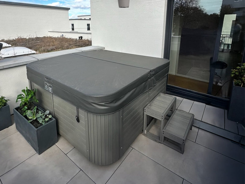 Abgedeckter WELUXIA Whirlpool mit Einstiegstreppe auf einer Dachterrasse