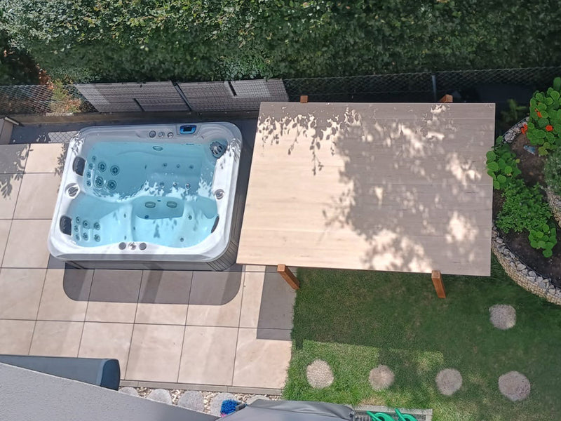 Draufsicht auf einen WELUXIA Whirlpool und eine benachbarte Holzplattform im Garten