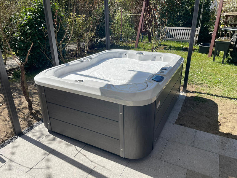 WELUXIA Whirlpool mit dunkler Verkleidung unter einer offenen Pergola im Garten