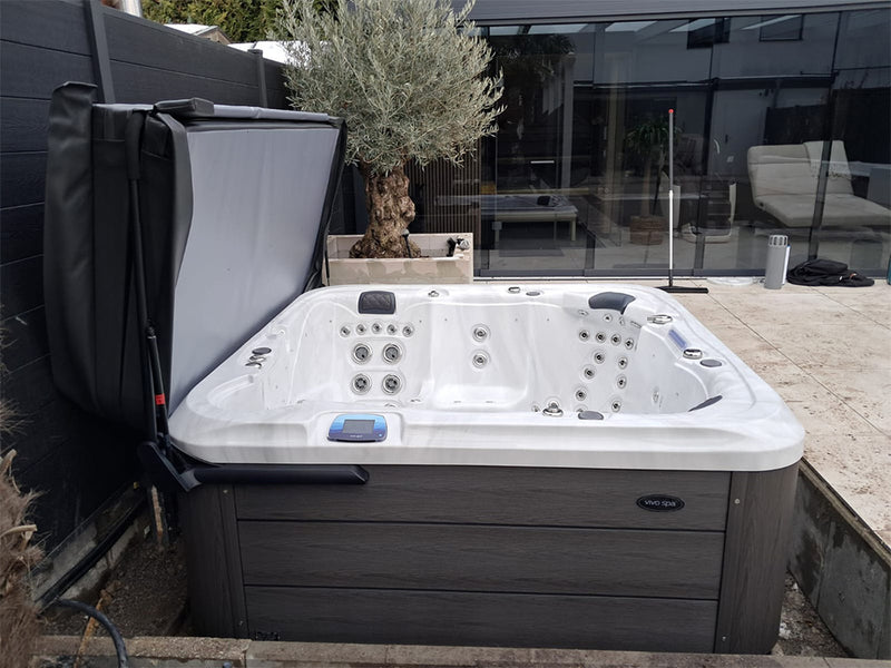 Geöffneter WELUXIA Whirlpool mit dunkler Holzoptik-Verkleidung auf einer modernen Terrasse