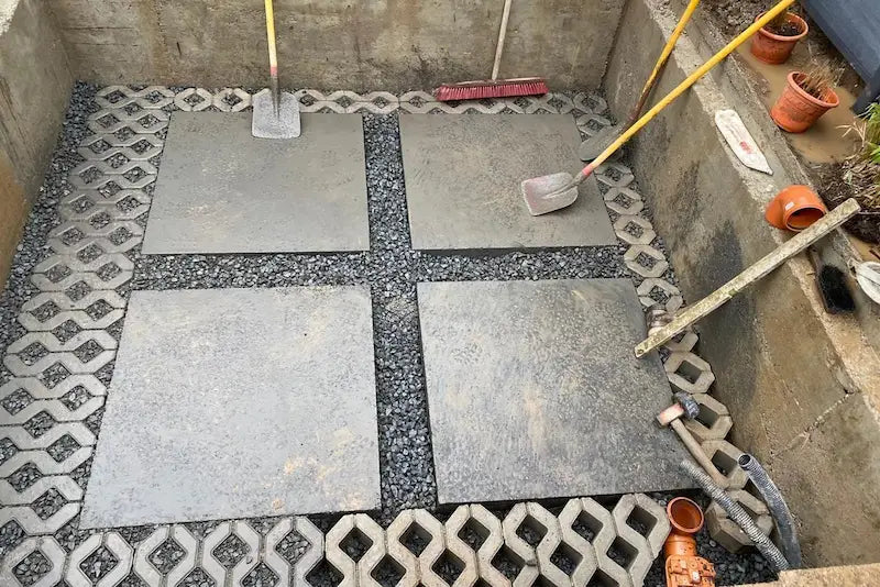 Vorbereiteter Whirlpool-Untergrund aus Betonplatten und Kies in einer ausgehobenen Grube