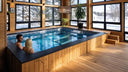 Paar entspannt in einem Indoor-Pool in einem hellen Holzraum mit Schneeblick