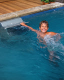 Lachender Junge schwimmt neben einer Gegenstromanlage in einem Pool