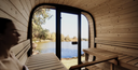 Gartensauna aus Holz mit Panoramafenster und Blick auf einen See
