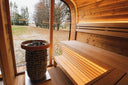 Innenraum der Round Cube Gartensauna mit Holzofen, Panoramafenster und beleuchteten Bänken