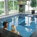 Paar entspannt in einem Indoor-Pool mit großen Panoramafenstern