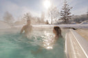 Paar im dampfenden Swim Spa in verschneiter Winterlandschaft
