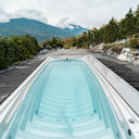 USSPA Swim Spa M auf einer dunklen Holzterrasse mit Blick auf bewaldete Berge