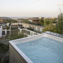 USSPA Swim Spa M mit Holzverkleidung auf einer erhöhten Terrasse mit Stadtblick