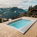 USSPA Swim Spa M auf einer hellen Holzterrasse mit Blick auf verschneite Berggipfel