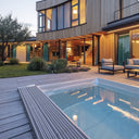 USSPA Swim Spa XL auf einer Holzterrasse vor einem beleuchteten modernen Haus am Abend