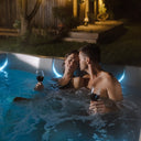 Paar mit Weingläsern im beleuchteten VIBES by USSPA Natura Whirlpool bei Nacht