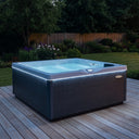 Beleuchteter VIVO SPA AUREA 4 Whirlpool mit dunkler Holzoptik-Verkleidung auf einer Gartenterrasse
