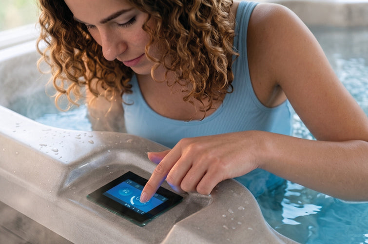 Frau bedient den Touchscreen am Rand eines Whirlpools