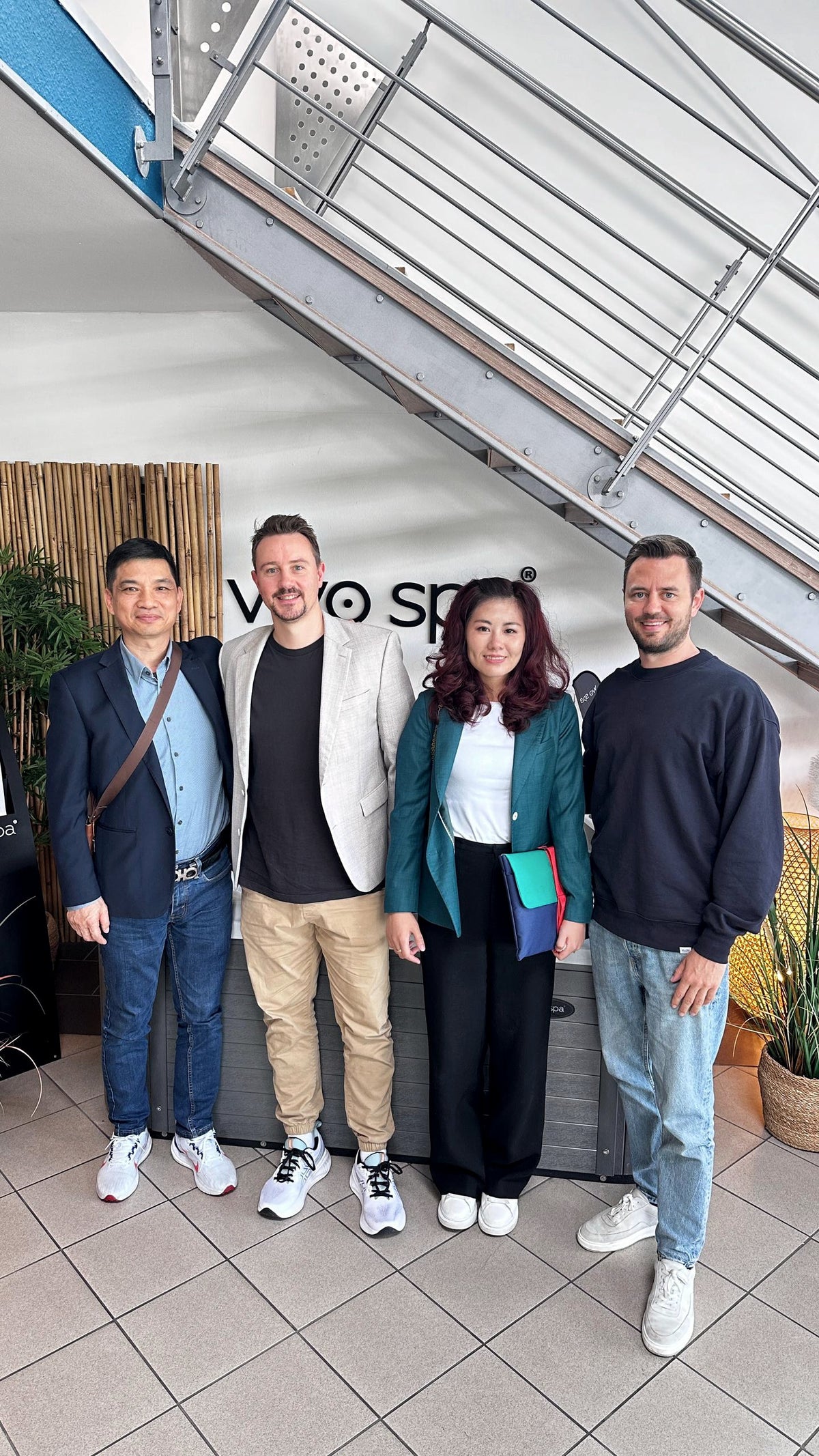 Vier Personen bei einem Lieferantenbesuch im Showroom vor dem vivo spa® Logo