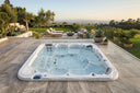 In die Steinterrasse eingelassener Outdoor-Whirlpool mit Blick über einen Garten