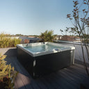 Outdoor-Whirlpool mit schwarzer Verkleidung auf einer bepflanzten Dachterrasse